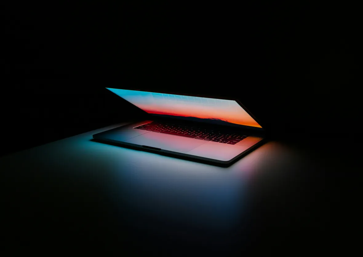 An open laptop glowing in a dark room