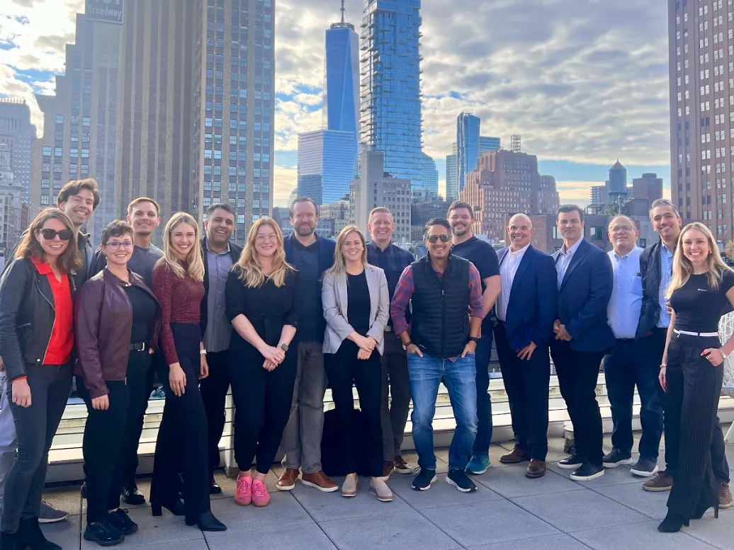 A group of attendees on a NYC rooftop at golden hour with Manhattan towers behind them