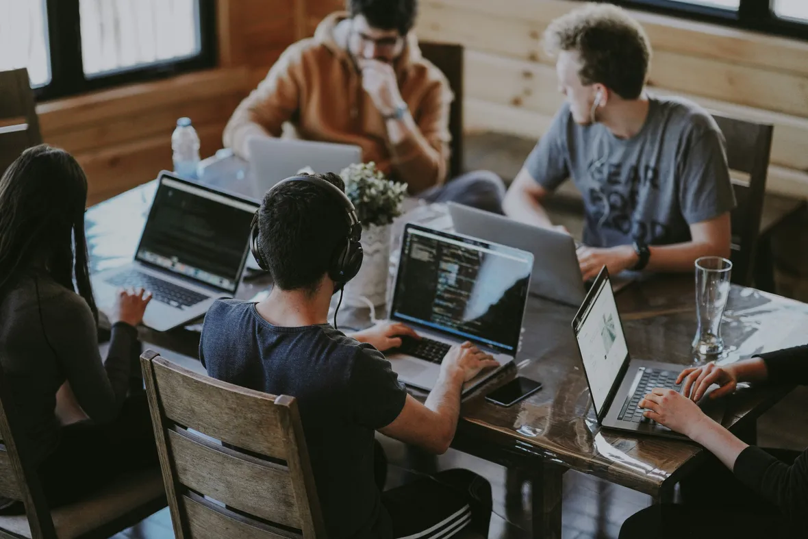 A team collaborating on laptops around a wooden table